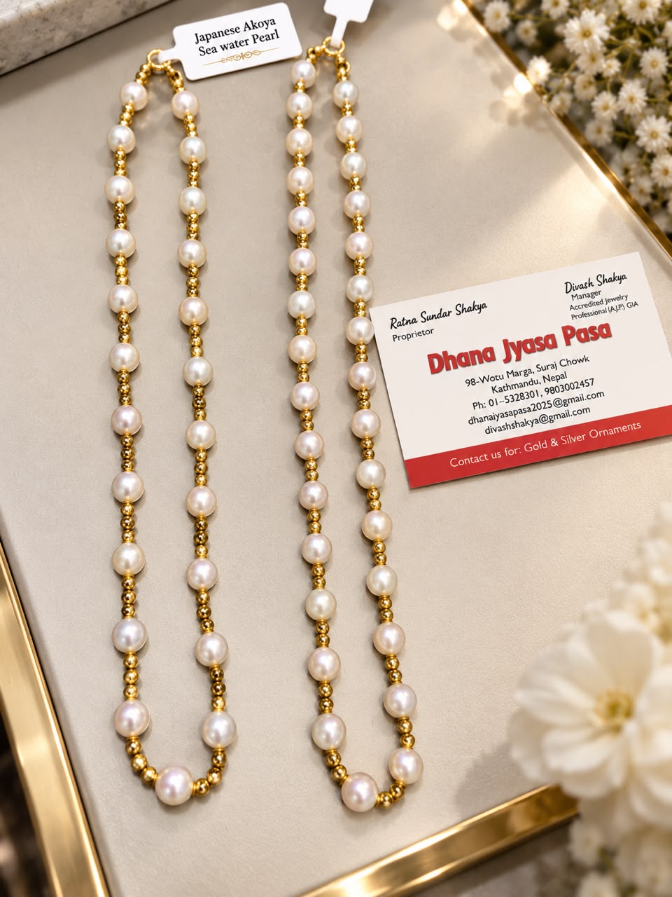 Japanese Akoya seawater pearl necklace with gold beads, beside the shop card