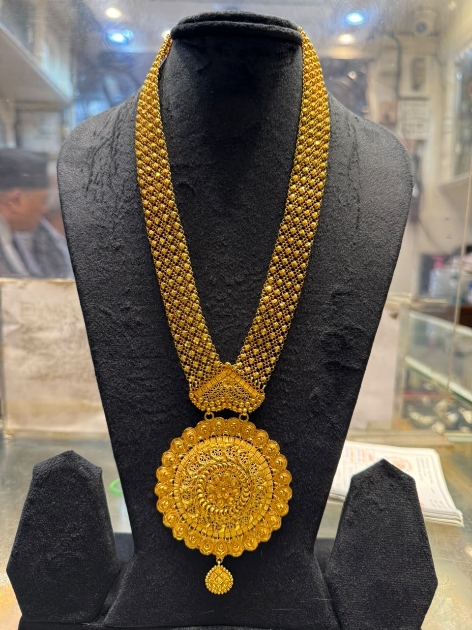 Gold mesh necklace with a large round filigree pendant and a small drop