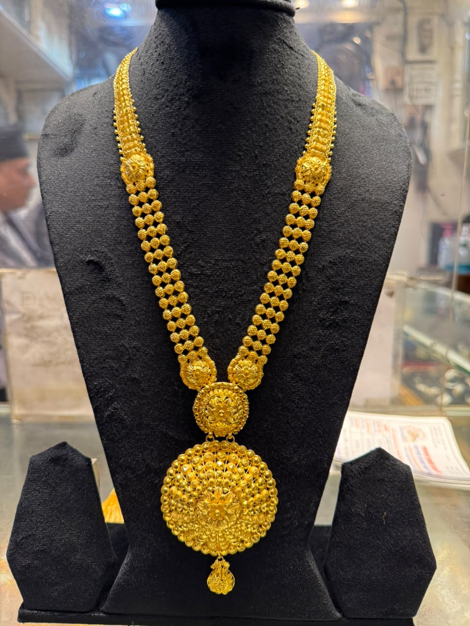 Gold necklace with beaded strands and a large round pendant
