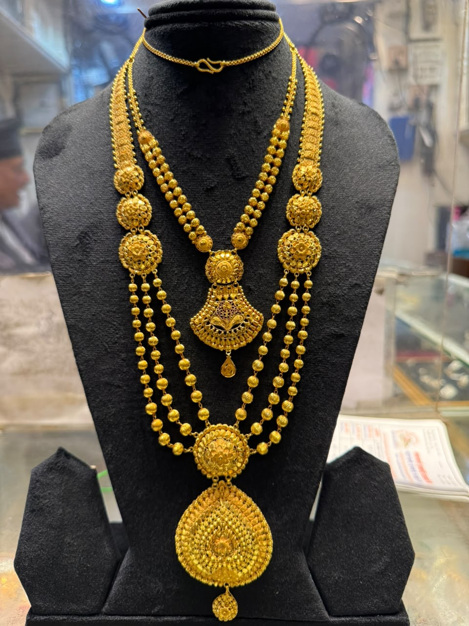 Layered gold necklace with round medallions and a large teardrop pendant